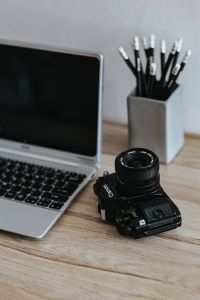 Black-and-white photos with a silver laptop, pencils and a camera