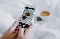 Woman taking photo of coffee in bed
