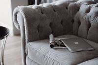 Silver laptop and a magazine on a grey sofa
