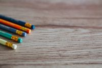 Colourful pencils with rubber erasers on a wooden desk