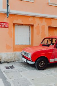 An old red Renault 4 car parked on the street in Izola, Slovenia