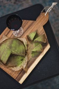 Delicious homemade matcha cake on a wooden board with wine