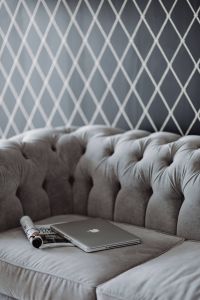 Silver laptop and a magazine on a grey sofa