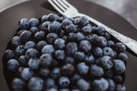Fresh blueberries on a black plate with vintage cutlery