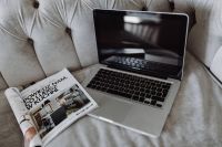 Silver Apple MacBook Pro with a magazine on a bed