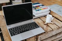 Silver laptop and a white mug on a wooden box table