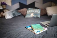 Laptop with books on a bed