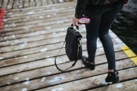 Woman with a black bag and a can of coke walking on a wooden pier