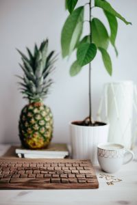 Wooden keyboard, cup of coffee, pineapple and golden jewellery