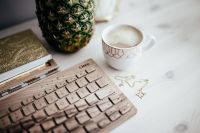 Wooden keyboard, cup of coffee, pineapple and golden jewellery