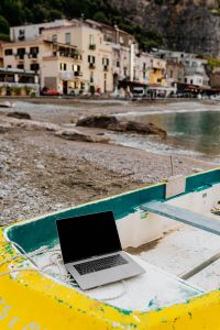 Kaboompics - Macbook laptop on a small yellow boat on the beach