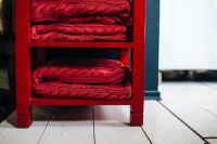 Red woolen fabric stacked on a little red cupboard