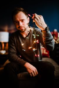 Kaboompics - A handsome young man with Christmas tree lamps