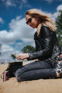Young woman wearing a leather jacket and sunglasses on the beach