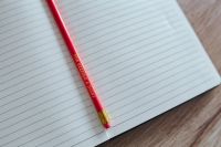 Notebook with a red pencil on a wooden desk