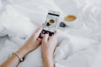 Woman taking photo of coffee in bed