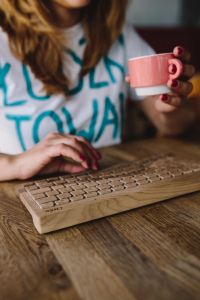 Woman with wireless wooden keyboard and cup of coffee