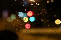 Colourful city lights through a wet car window