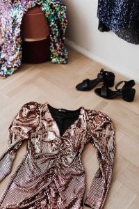 Kaboompics - colored sequin dresses and boots lie on a wooden parquet, blue dress hang on the white wall