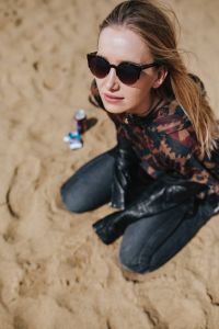 Young woman wearing a leather jacket and sunglasses on the beach