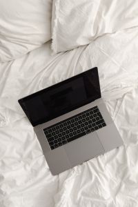 Kaboompics - Working with a laptop in bed - white cotton bedding