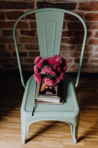 Kaboompics - Industrial pale green metal chair with a bouquet of pink flowers and books on it