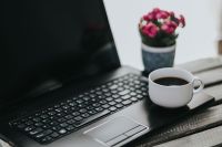 Little pink flowers with a coffee and a black laptop