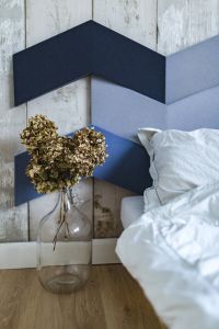 An ornamental golden plant in a jar by the bed with white sheets