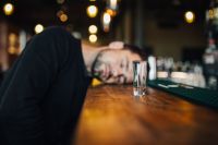 Drunk and unconscious man lying on a counter in a classy bar