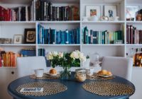 Round breakfast table with white flowers by the bookcase