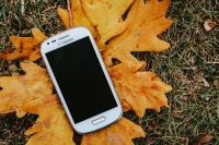 White smartphone on a yellow leaf
