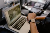 Kaboompics - Man with notebook sitting inside an airplane & looking at watch