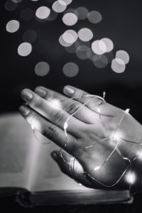 Female hand, fairy lights, book