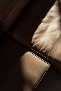 A moody close-up of a leather sofa with natural light casting soft shadows emphasizing the texture of the material