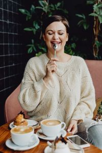 Kaboompics - A woman drinks coffee and eats a dessert in a café