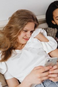 Kaboompics - Teens sit together on the couch and use phones