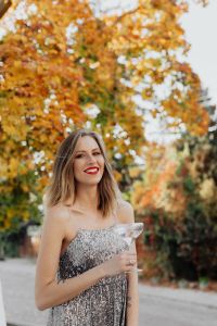 Blond Woman in a Sequin Dress is Holding a Glass of Champagne, Autumn