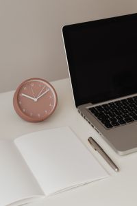 Detail of desk with laptop - supplies - notepad - clock - time - pen
