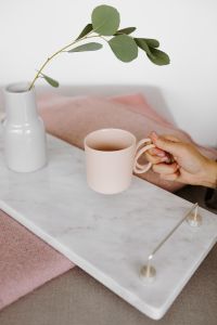 Kaboompics - A woman's hand holds a pink mug or cup over a marble tray