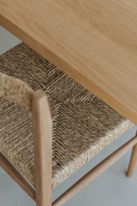 A close-up of a natural wicker chair paired with a smooth wooden table