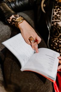 A woman with a large ring and a golden watch writes down in the calendar