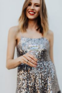 Blond Woman in a Sequin Dress is Holding a Glass of Champagne, White Background