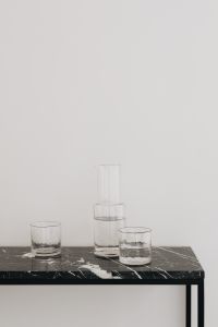 Kaboompics - Water in a transparent glass carafe and glasses on a black marble console