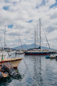 Boats moored in a marina in Naples, Vesuvius volcano in the background