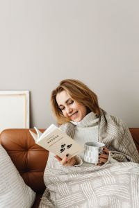 Kaboompics - Smiling woman reading a book - mug of tea