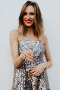 Blond Woman in a Sequin Dress is Holding a Glass of Champagne, White Background