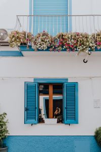 Kaboompics - White building with blue shutters and flowers on the balcony