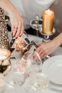 Kaboompics - A woman decorates a Christmas table with silver decorations and white porcelain tableware