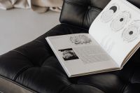 Kaboompics - An open book lies on a black leather Barcelona chair