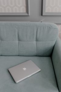 MacBook laptop lying on mint couch